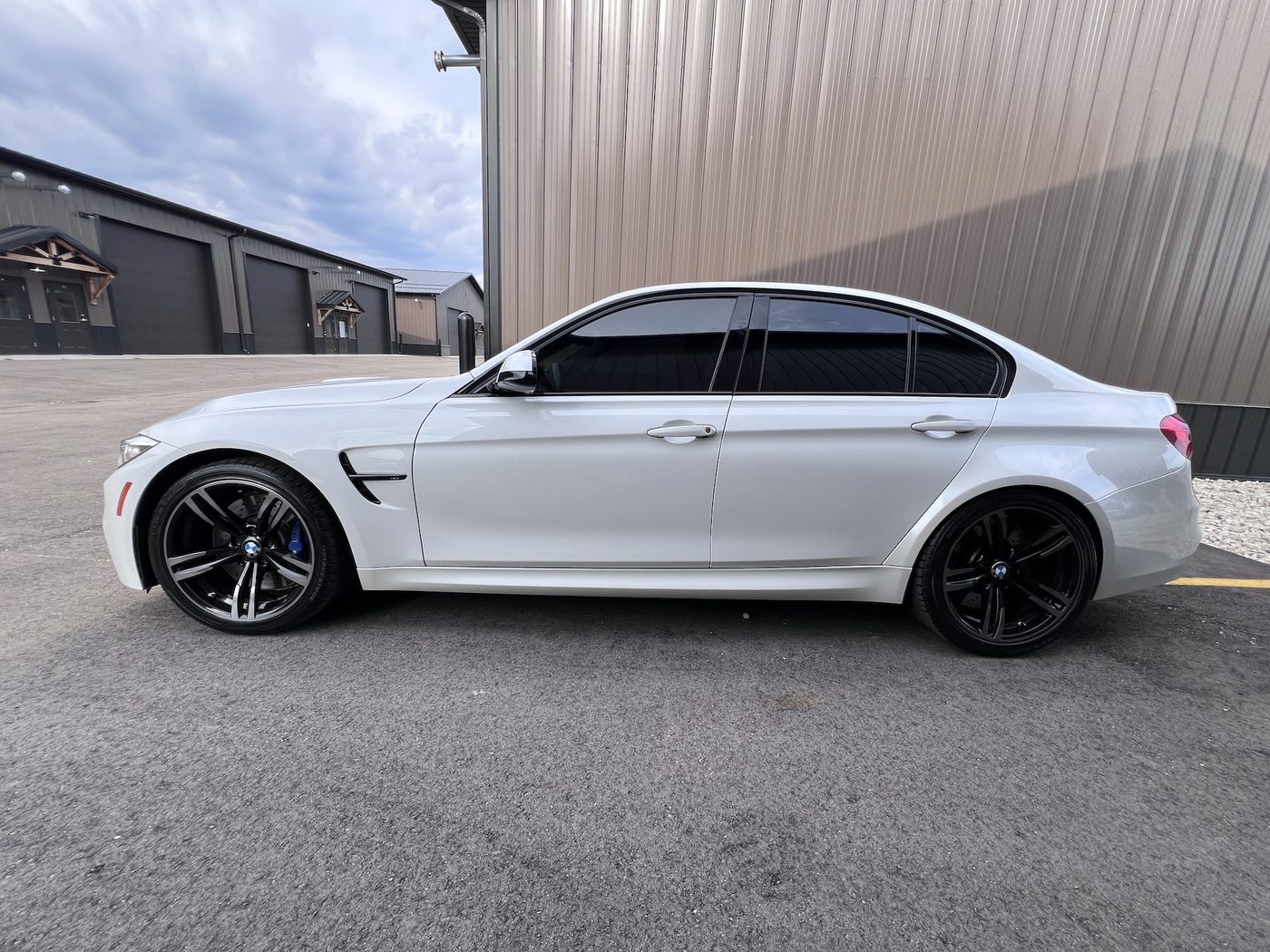 2015 BMW M3, white, in profile beside the building