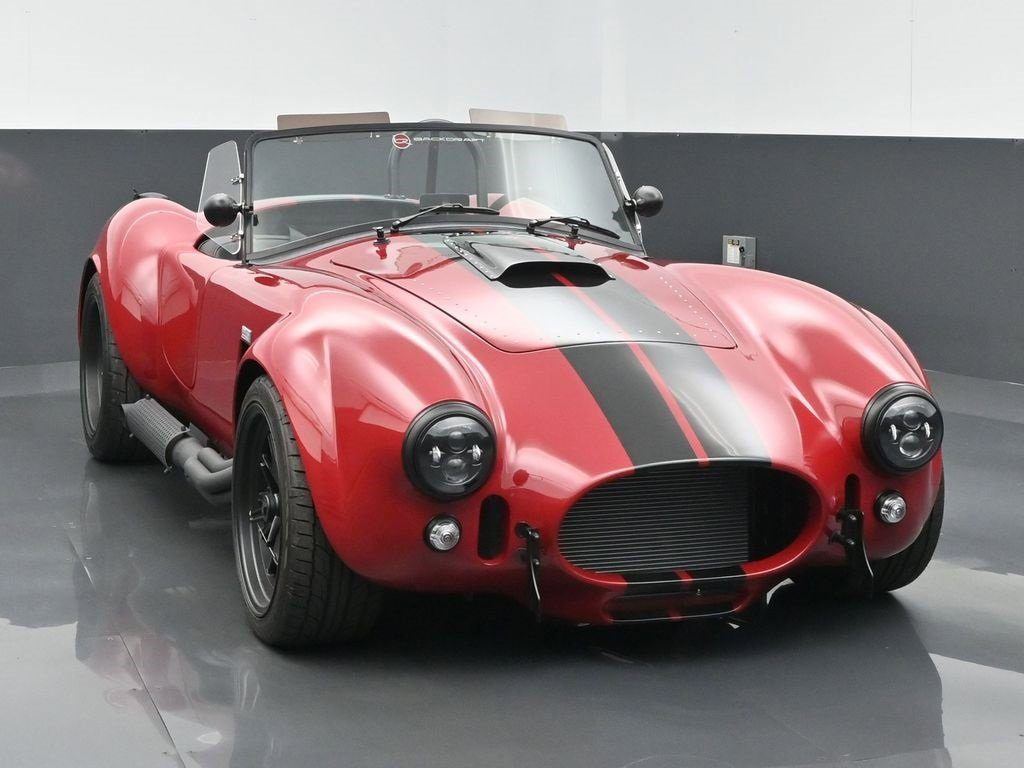Red Cobra roadster with a gunmetal stripe on a studio turntable